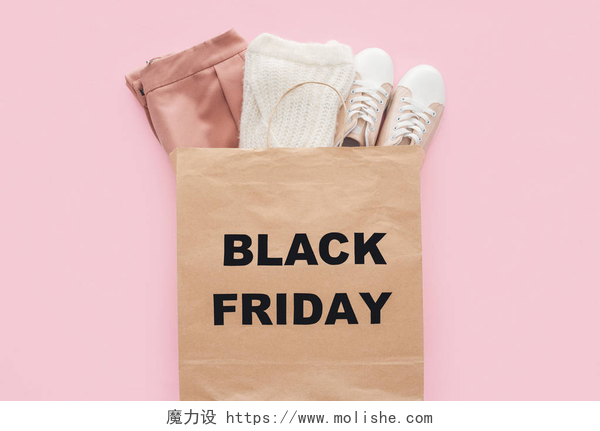 带有黑色星期五标志的袋子里的时尚衣服最热门的时尚服装在购物袋与黑色星期五标志被隔离粉红色 